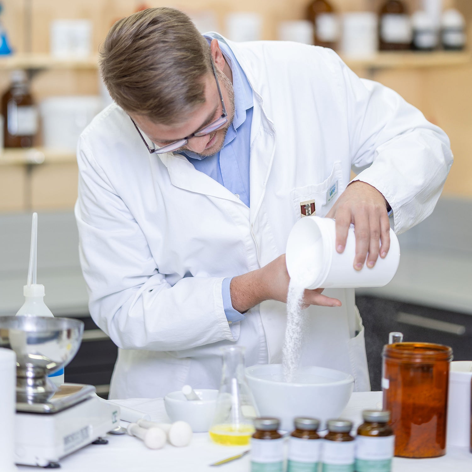 Wissenschaftler im Labor gießt Pulver in eine Schale zur Herstellung von Nahrungsergänzungsmittel