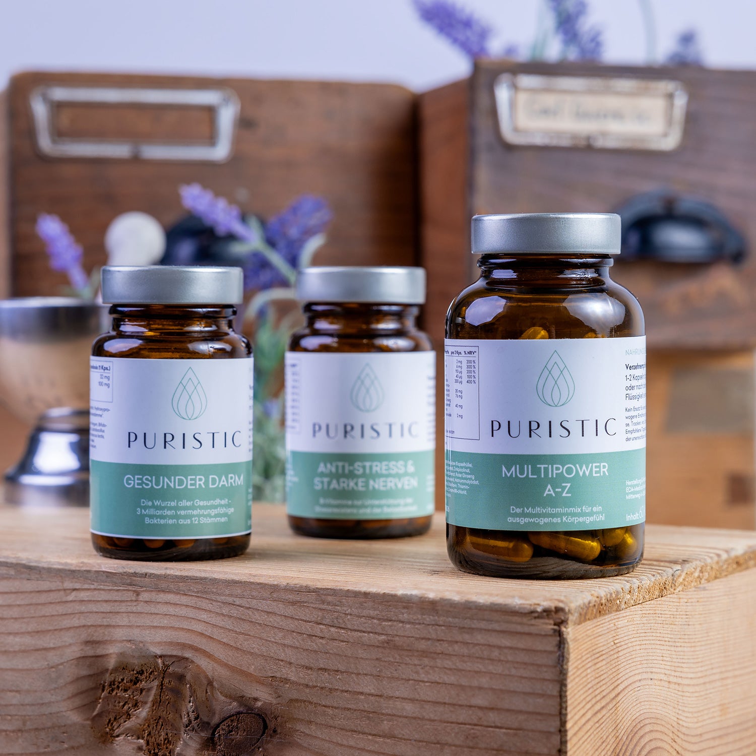 Drei verschiedene Puristic Nahrungsergänzungsprodukte in Kapselboxen auf Holzbrett mit Lavendel
